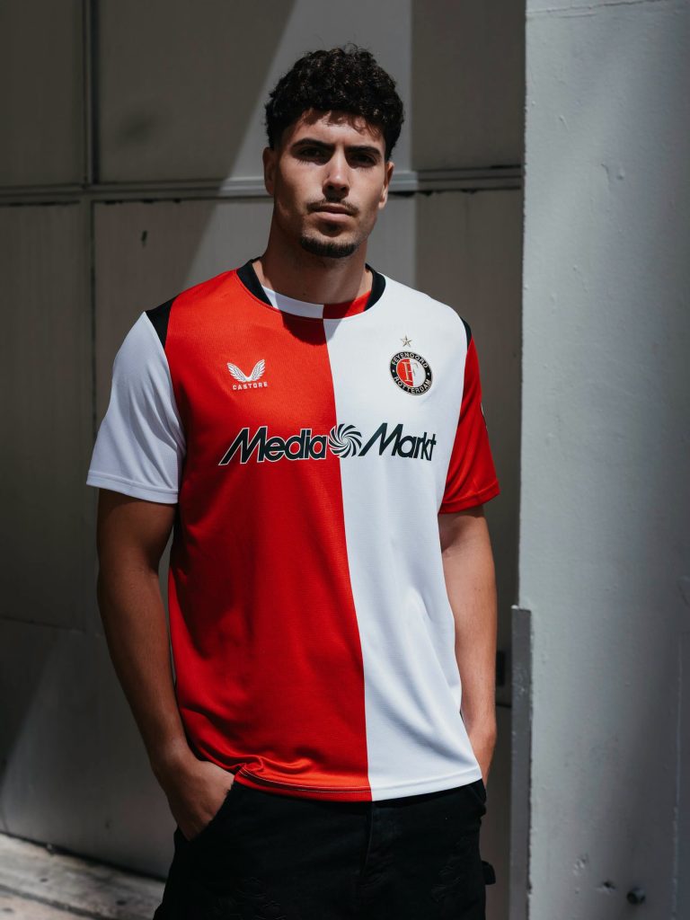 Een model draagt het rood-witte thuisshirt van Feyenoord voor het seizoen 2026-2027, met de sponsor MediaMarkt