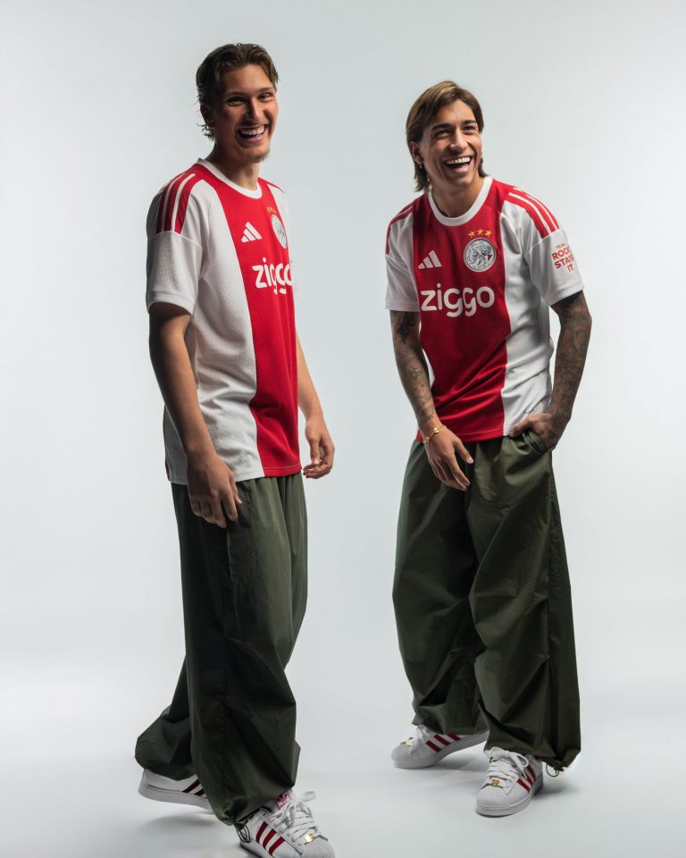 Twee modellen tonen het thuisshirt van Ajax voor 2026-2027 ten voeten uit, van voren en van achteren