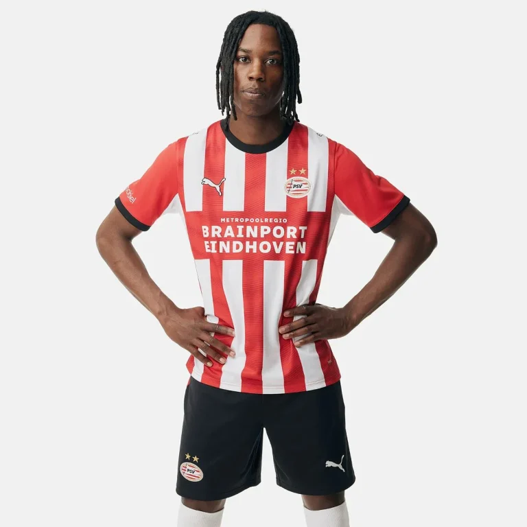 Een model draagt het rood-wit gestreepte thuisshirt van PSV voor het seizoen 2026-2027, met de sponsor Brainport Eindhoven