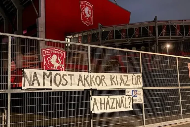 Hongaars spandoek met de tekst Na most akkor ki az ur a haznal op een hek bij de bezoekersingang van De Grolsch Veste, met het clublogo van FC Twente op de achtergrond